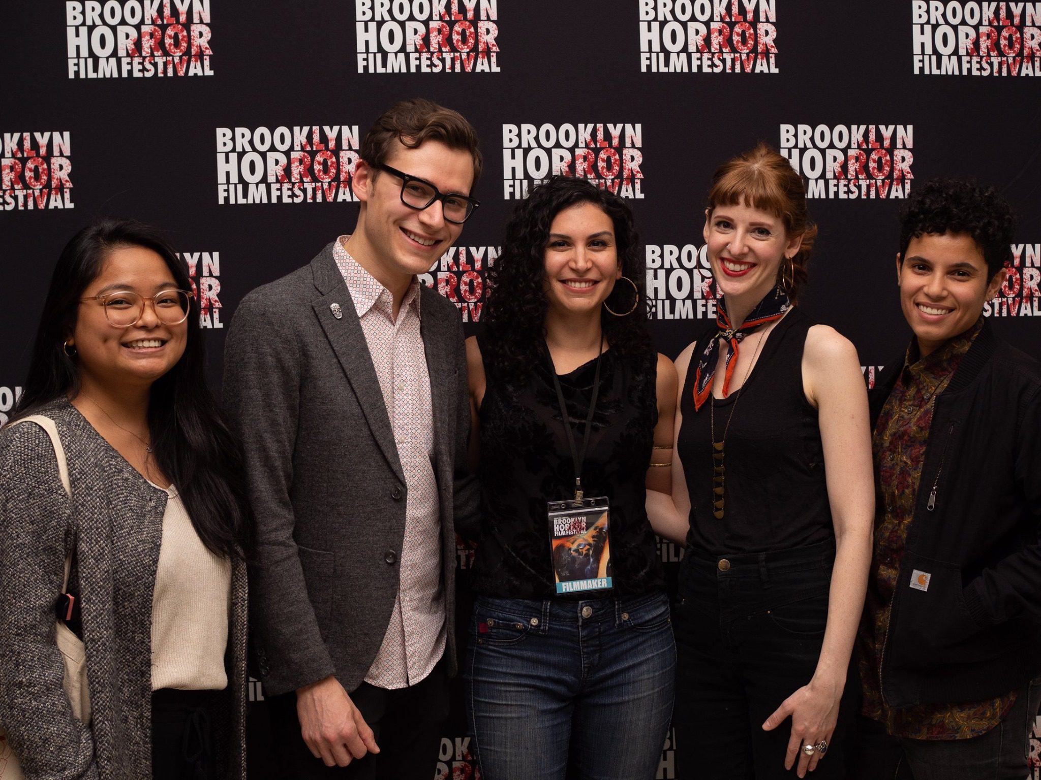 A group of Brooklyn Horror Film Festival attendees smiling and wearing festival badges