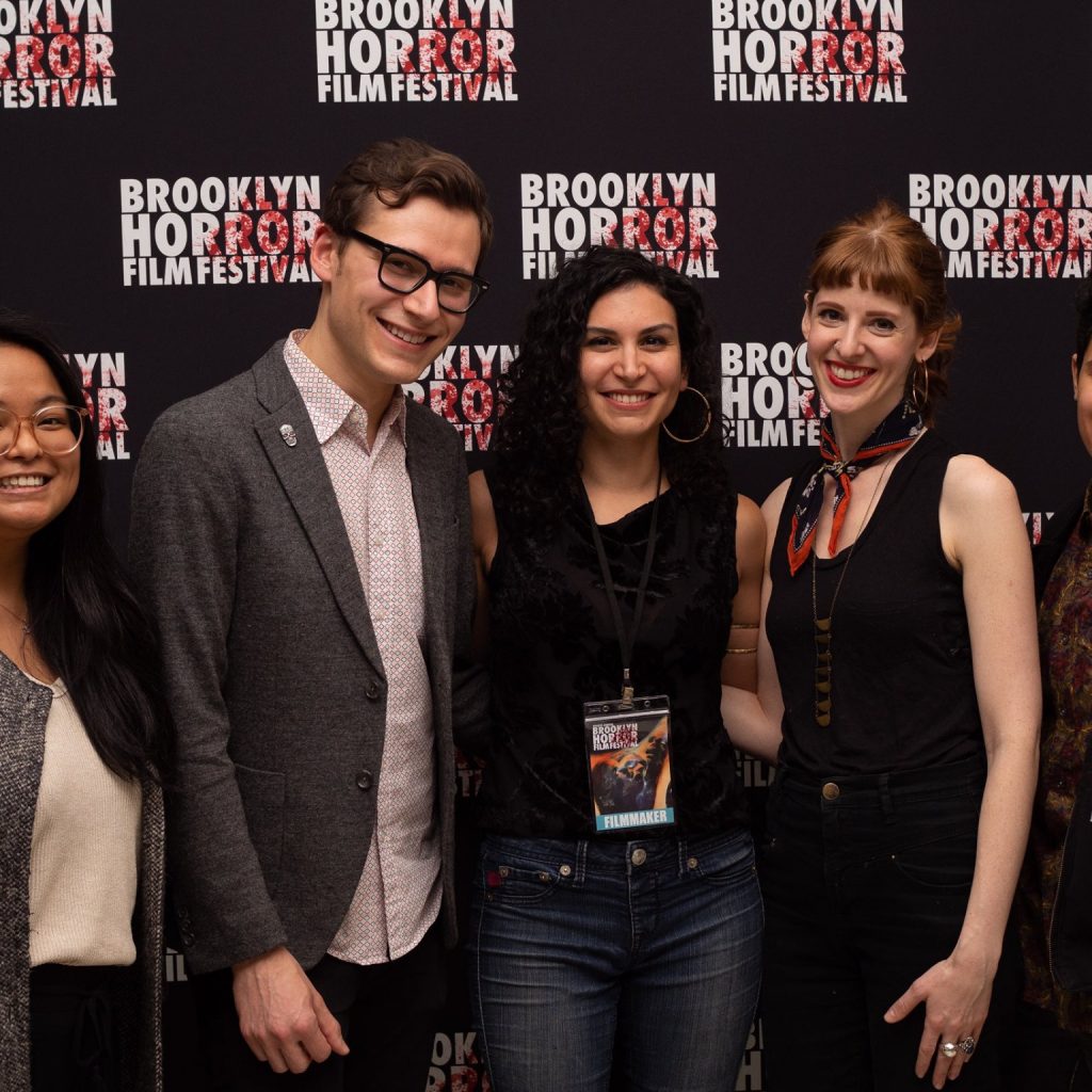 A group of Brooklyn Horror Film Festival attendees smiling and wearing festival badges